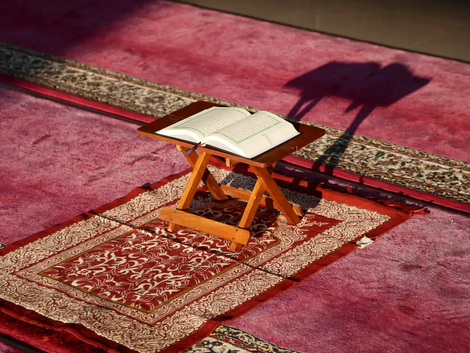 Quran on a stand over a red patterned carpet