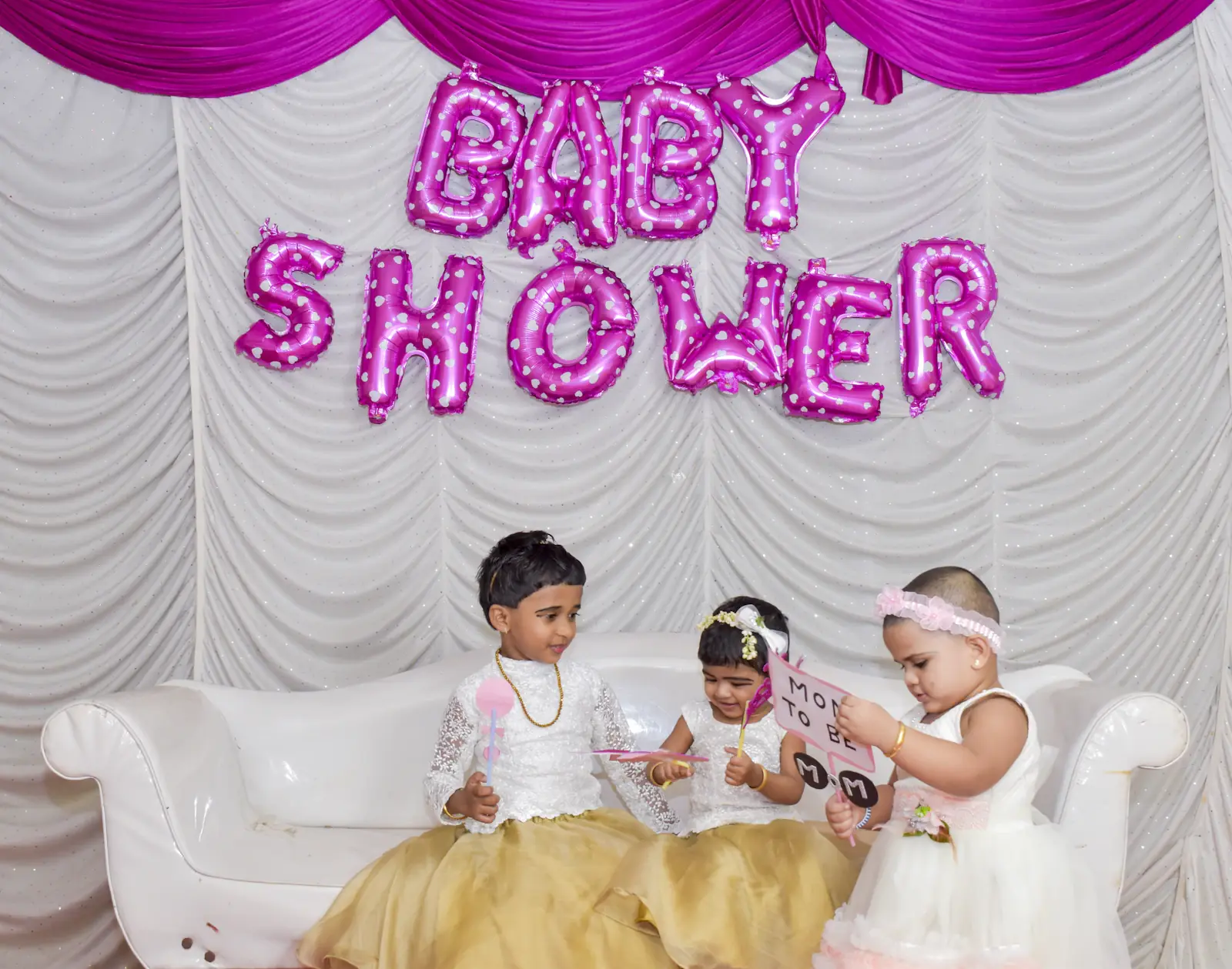 Baby shower backdrop with balloon letters and a decorated sofa