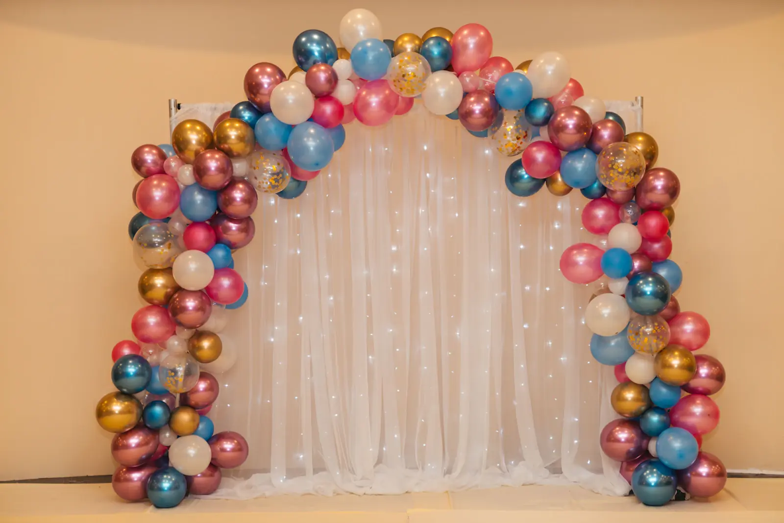 Metallic balloon arch over a draped birthday backdrop