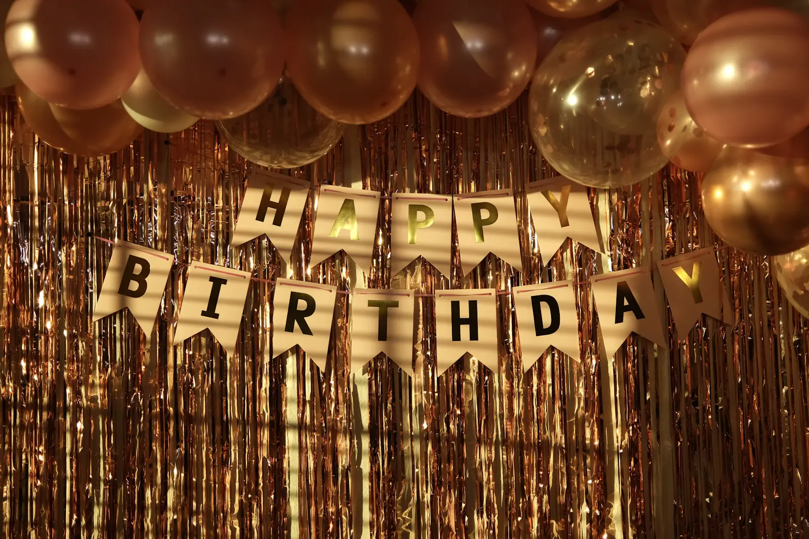 Gold balloons and a Happy Birthday garland on a party wall