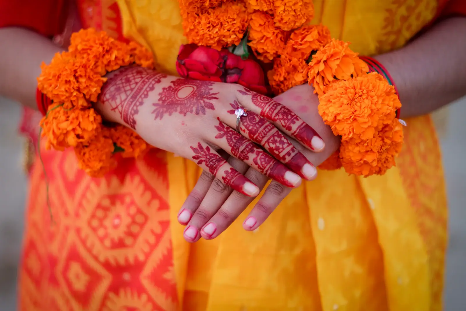 Bride with henna hands wearing orange marigold garlands