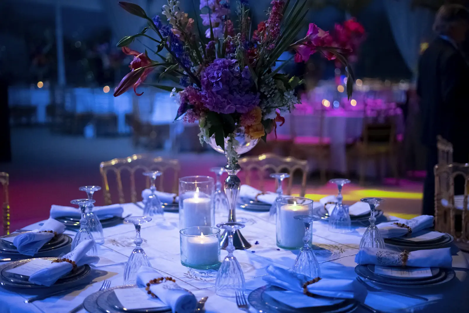 Blue lit event table with floral centerpiece and candles