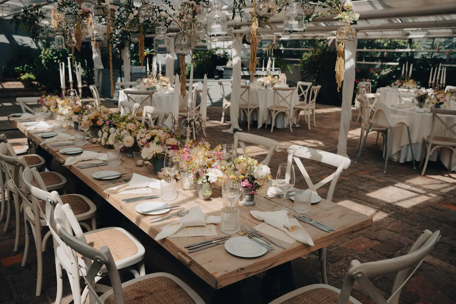 Wedding reception tables with floral centerpieces under a glass roof