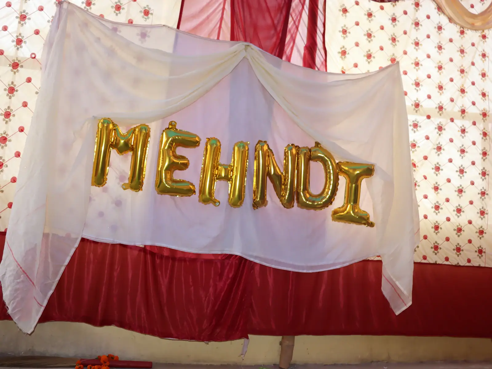 Diy Mehndi Decor - Mehndi balloon letters on a red and white draped backdrop