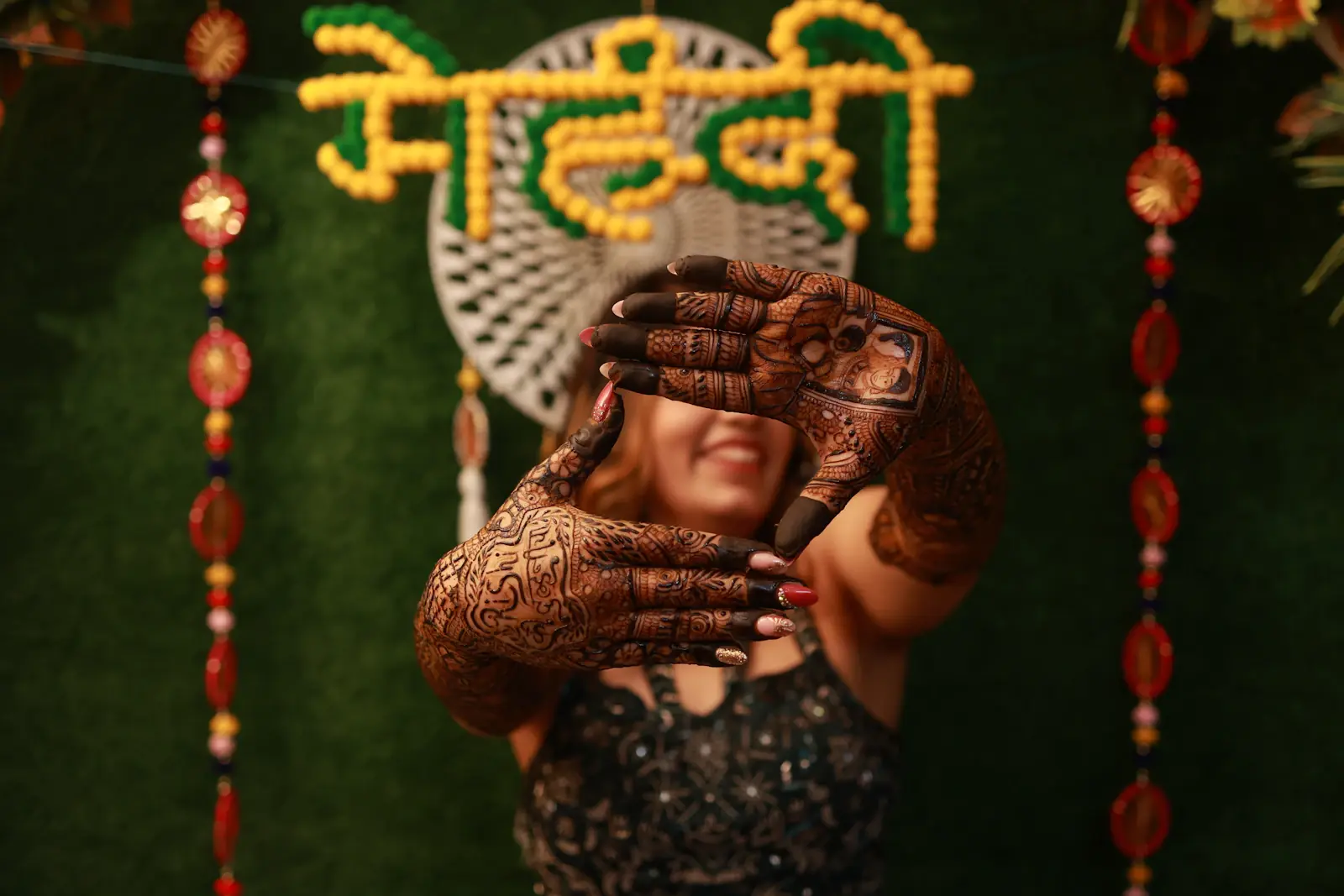 Bride showing henna hands in front of a neon mehndi sign