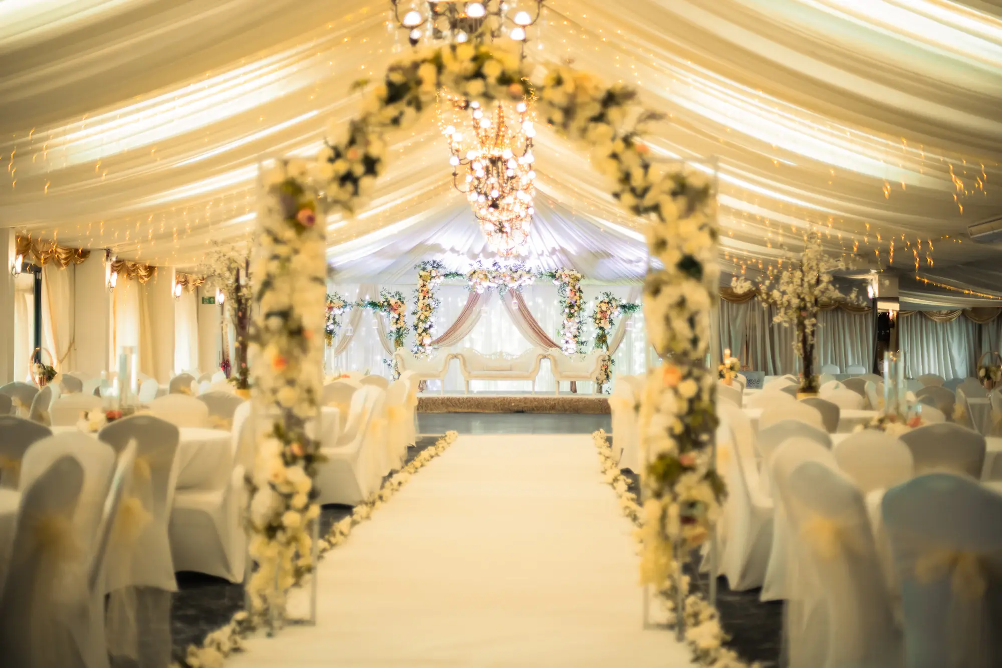 Wedding hall with a white floral aisle and draped ceiling