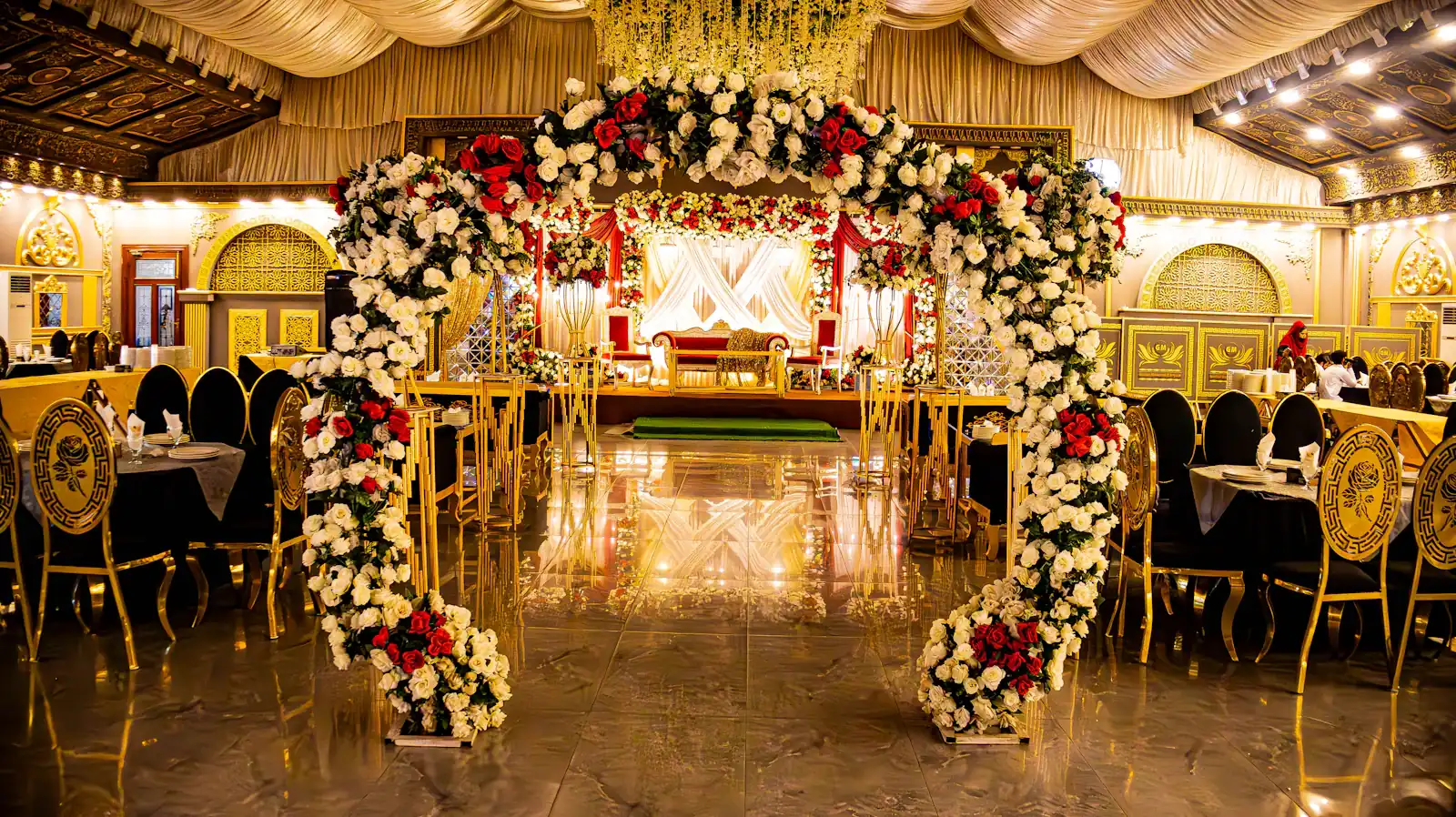 Wedding stage with a gold floral arch in a banquet hall
