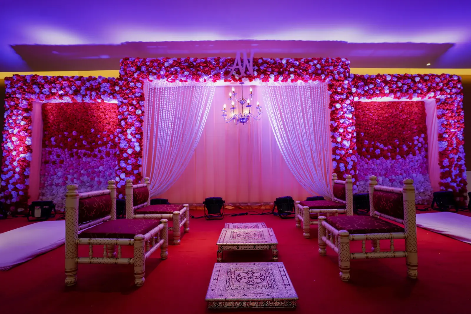 Purple lit floral wedding stage with white drapes